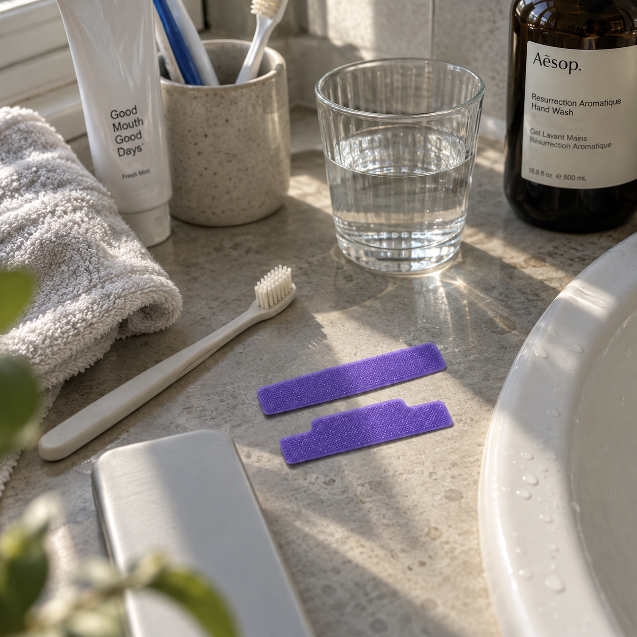 Whitening strips på badrumsbänk med tandborste och vattenglas